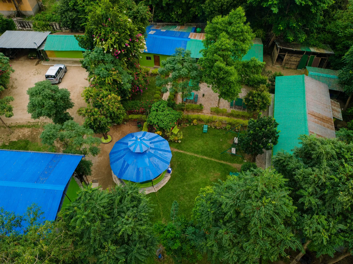 Drone view looking down over Shuklaphanta Jungle Cottage grounds, gardens and cottage rooftops